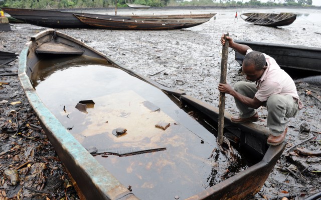 An indigene of Bodo Ogoniland tries to separate the crude oil from water in a boat with a stick at the Bodo waterways polluted by oil spills attributed to Shell equipment failure. Credit Pius Utomi Ekpei
